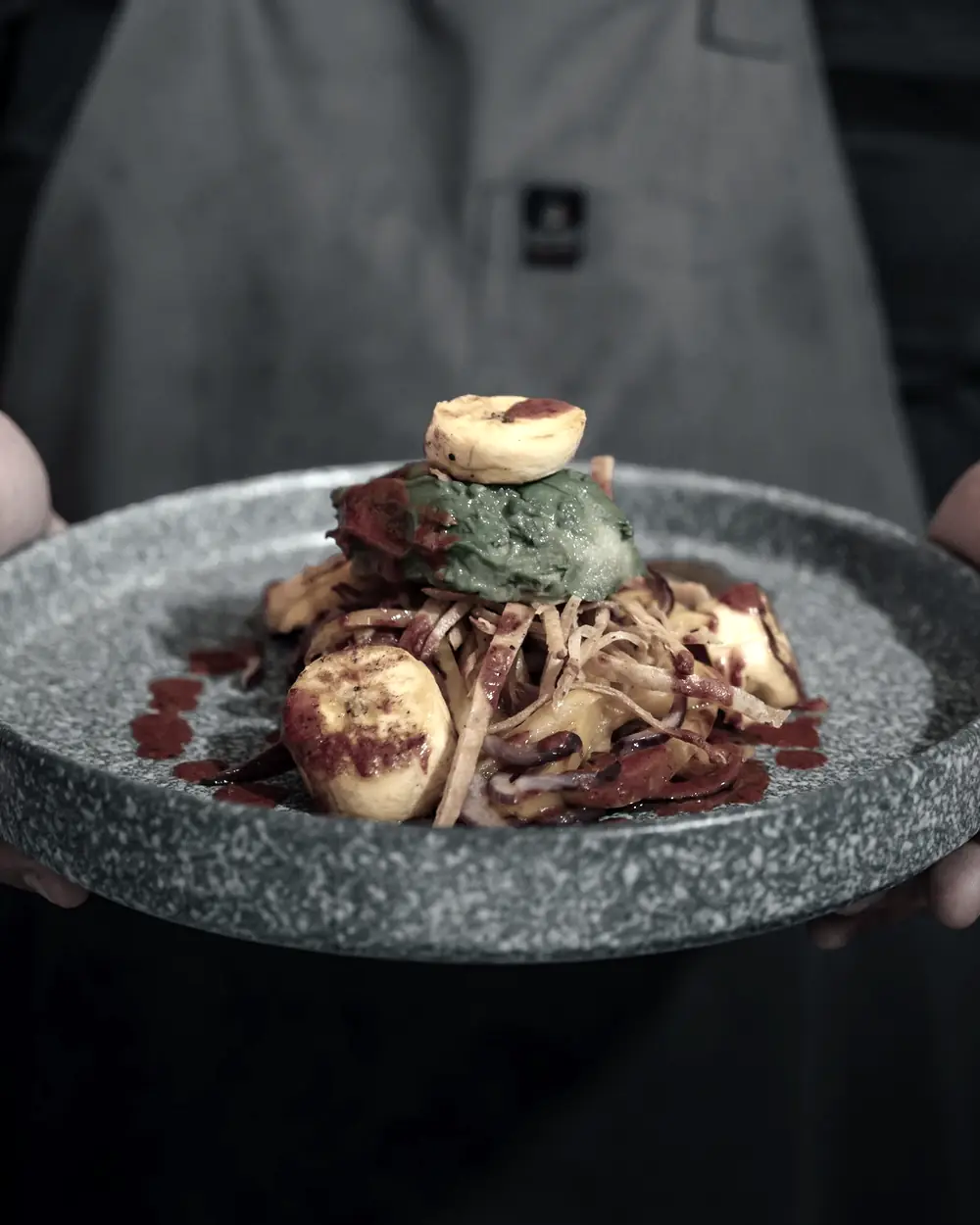 Mains présentant une assiette de pierre au moment du service